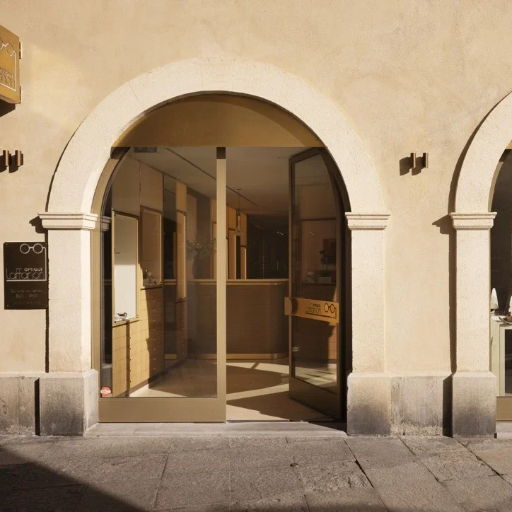 Façade et décoration intérieure de la boutique Laffanon à Nîmes, utilisant du laiton doré, du bois clair et des miroirs monumentaux pour un rendu luxueux.